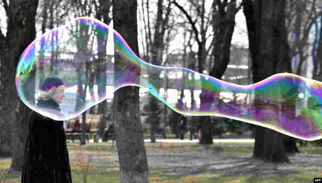 A woman walks next to a soap bubble made by a street artist in the center of Ukraine's capital, Kyiv.
