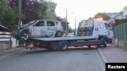 Kamion odvozi Izgoreli automobil ispred rezidencije gradonačelnika Leileroza, u blizini Pariza, 2. jula 2023.