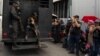 FILE - A truck with detainees passes by relatives of people detained during protests in Venezuela over the country's contested presidential election outside a police headquarters, in Caracas, Venezuela, Aug. 1, 2024. 