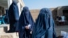 FILE - Afghan women wait for food in the Baraki Barak district of Logar province, Jan. 7, 2024. A United Nations report released in December said the Taliban are sending to prison women who complain to them about gender-based violence and do not have male relatives to stay with.