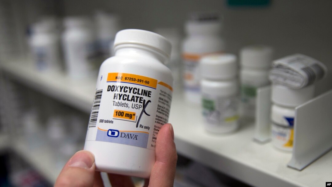 FILE - A pharmacist holds a bottle of the antibiotic doxycycline hyclate in Sacramento, California, July 8, 2016. 