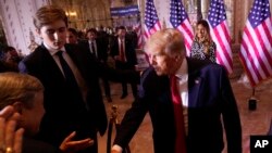 FILE - Barron Trump, left, watches as his father former President Donald Trump greets people after announcing he is running for president for the third time as he speaks at Mar-a-Lago in Palm Beach, Nov. 15, 2022.