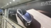 FILE - A woman walks near an advertisement billboard of a new electric vehicle from Chinese automaker Dongfeng at a train station in Beijing, April 20, 2024.