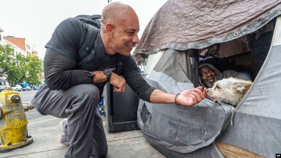 Dr. Kwane Stewart approaches the dog Popcorn protecting his owner's tent in the Skid Row area of Los Angeles on June 7, 2023.
