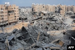 Displaced Palestinians walk amid the rubble of houses destroyed by Israeli bombardment in the Hamad area, west of Khan Younis in the southern Gaza Strip, March 14, 2024.