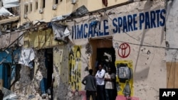 FILE - People stand near a building destroyed after a deadly siege by al-Shabab militants in Mogadishu, Somalia, Aug. 21, 2022. The Somali government said on Sunday that its elite soldiers have kllled 21 al-Shabab militants and wounded 10 others.