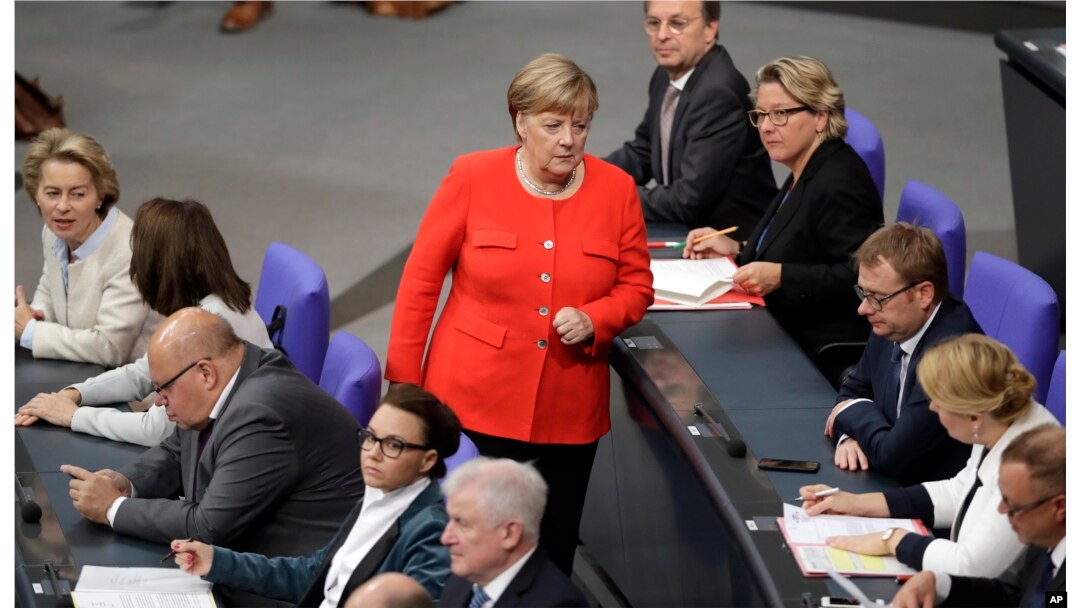 FILE - German Chancellor Angela Merkel, center, walks between ministers and state secretaries during a meeting of the German federal parliament, Bundestag, at the Reichstag building in Berlin, Germany, Sept. 27, 2018.