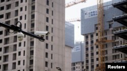 资料照：上海一处正在修建的公寓楼盘旁竖立着一个监控摄像头。（2022年7月20日）