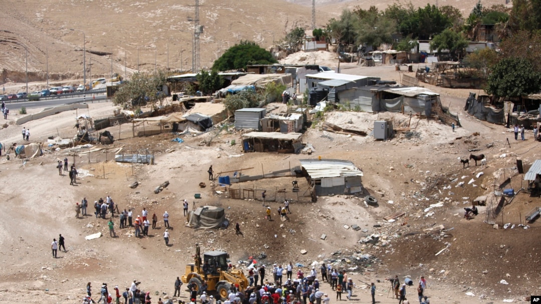 FILE - Palestinians gather around a bulldozer in Khan al-Ahmar, July 4, 2018. Israeli police scuffled with activists at a West Bank Bedouin community ahead of its planned demolition.
