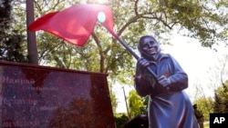 Një skulpturë e një gruaje ukrainase që mban një flamur të epokës sovjetike (Mariupol, Ukrainë, 9 maj 2022)
