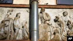 Një zog qëndron mbi një basoreliev të epokës sovjetike
