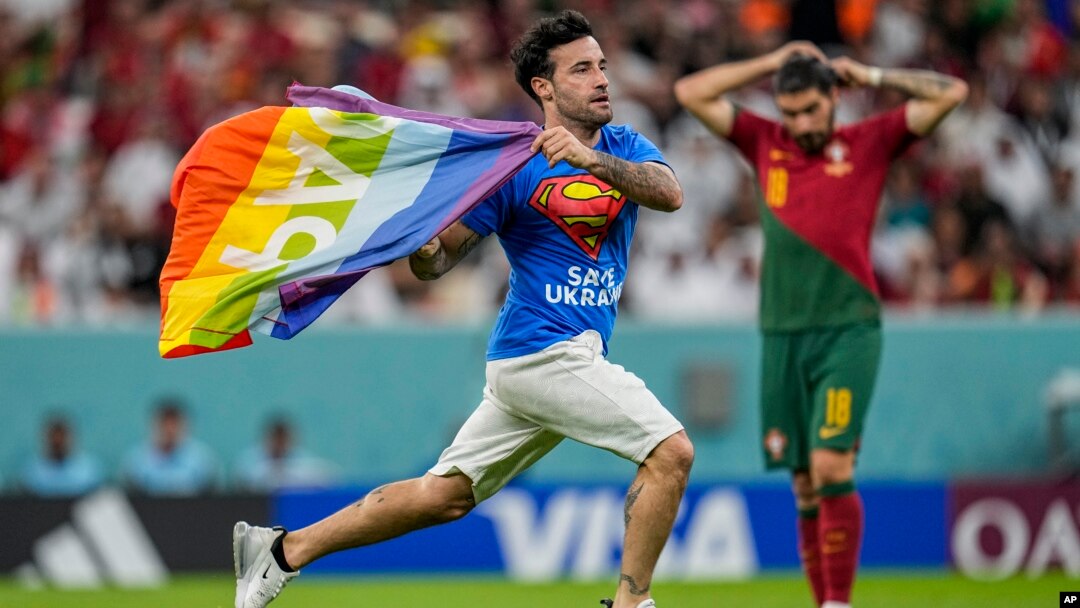 Yon manifestan kouri monte sou teren foutbol la ak yon drapo lakansyel nan men li, pandan match Potigal ak Urugwe, nan Mondyal Foutbol Qatar la, 28 Nov. 2022. 