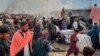 People gather beside a burnt truck destroyed by Afghan shelling, in Chaman, a town in Pakistan's southwest near Afghan border, Dec. 11, 2022.