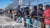 FILE - Afghan men stand in a queue as they wait to receive food aid from a non-governmental organization (NGO) in Kabul, Jan. 3, 2023. Aid groups say they have been pushed against a wall by the Taliban prohibiting Afghan women from working for NGOs.