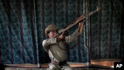 FILE - Kahlan, a 12-year-old former child soldier with Yemen's Houthi rebels, demonstrates how to use a weapon at a camp for displaced persons where he took shelter with his family in Marib, Yemen, July 27, 2018.