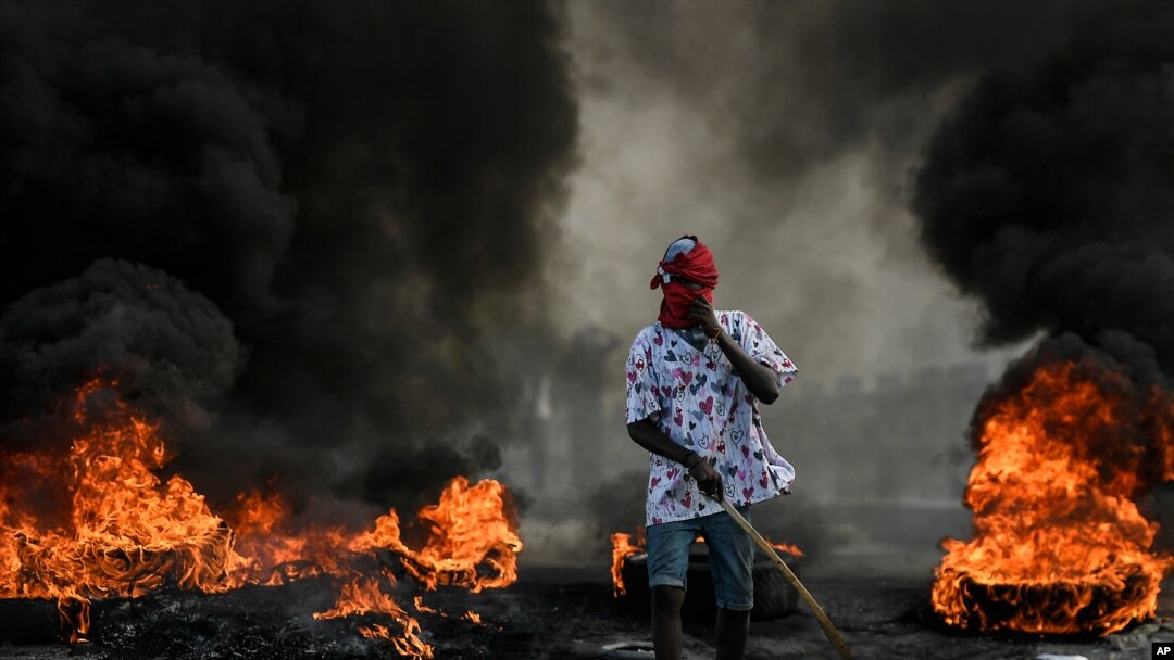 A protester demanding justice for the assassinated President Jovenel Moise stands near a burning barricade in Cap-Haitien, Haiti, July 22, 2021.