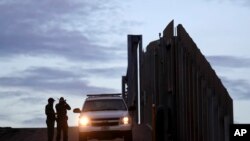FILE - In this Nov. 21, 2018, photo, U.S. Border Patrol agents stand by a vehicle near one of the border walls separating Tijuana, Mexico, and San Diego, in San Diego.