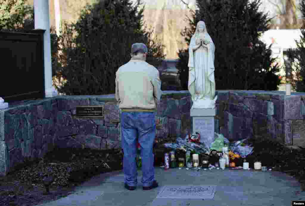 A man bows his head as he stands at a makeshift memorial, outside Saint Rose of Lima Roman Catholic Church in Newtown, Connecticut, Dec. 15, 2012.