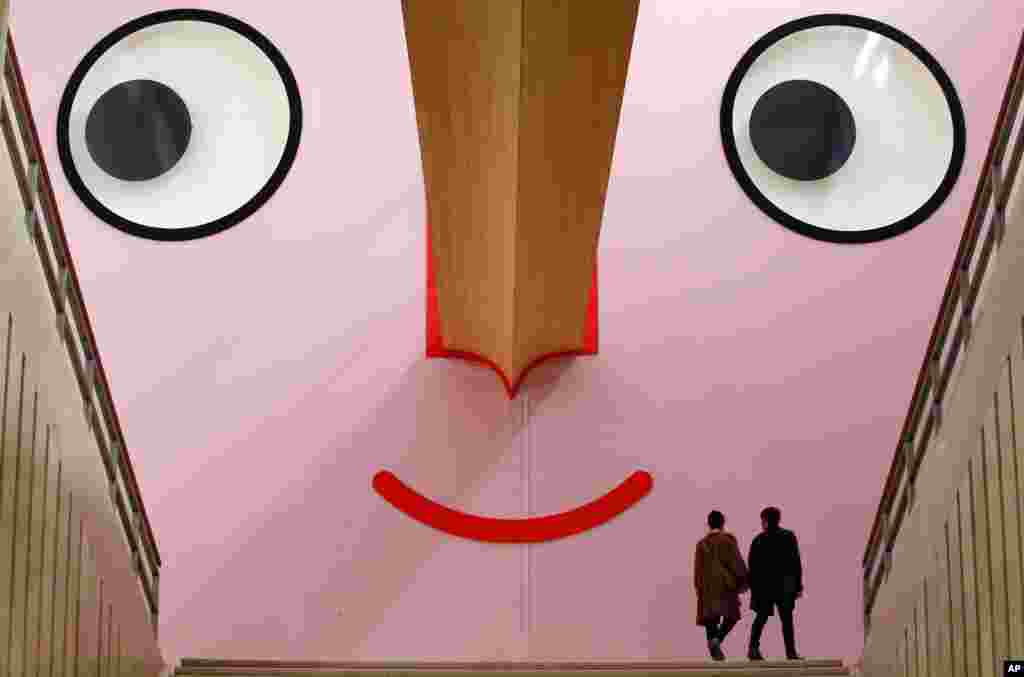 People walk at the entrance of the "Giro Giro Tondo design for children" exhibition, at the Triennale museum, in Milan, Italy.