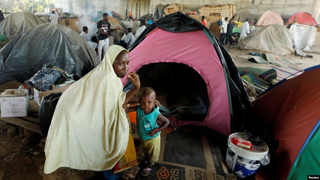 FILE - An African migrant sits with her son beside her tent at a makeshift camp set up under the bridge of a motorway on the outskirts of Algiers, Algeria, June 28, 2017. 