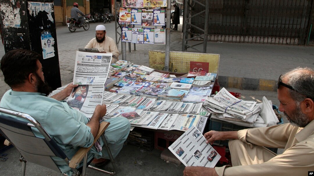 People read copies of morning newspapers carrying headline news of the Supreme Court decision against Prime Minister Imran Khan's ruling, at a stall, in Peshawar, Pakistan, April 8, 2022. 