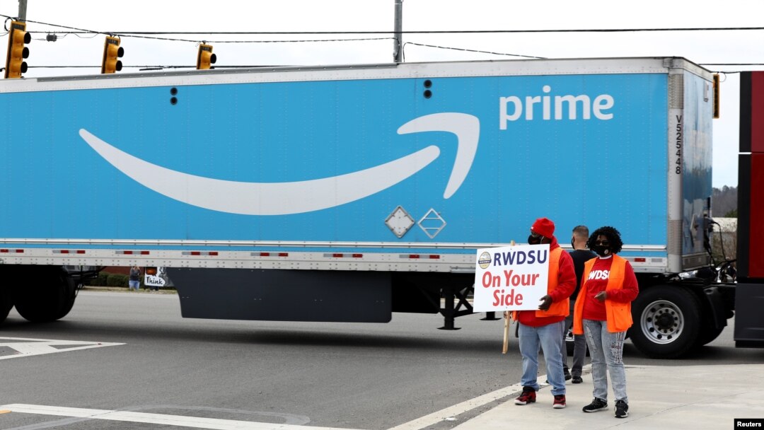 People hold a banner at the Amazon facility as members of a congressional delegation arrive to show their support for workers who voted on whether to unionize, in Bessemer, Alabama, March 5, 2021