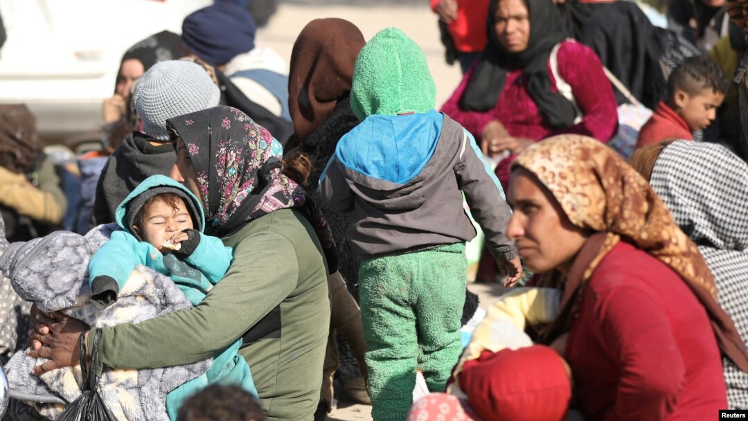 Displaced women who fled the Aleppo countryside sit with their children in Tabqa, Syria, Dec. 4, 2024.