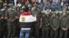 An anti-Mursi protester with an Egyptian flag around his shoulders talks to soldiers standing guard outside the Egyptian presidential palace in Cairo December 9, 2012.