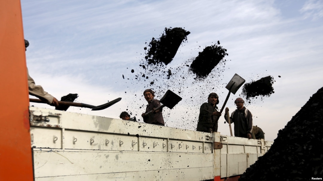 FILE - Laborers unload coal from a truck at a coal dump site in Kabul, Afghanistan.