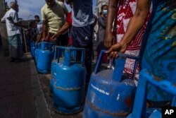 People wait in a queue with empty cylinders to buy domestic gas at a distribution center, in Colombo, Sri Lanka, July 12, 2022.