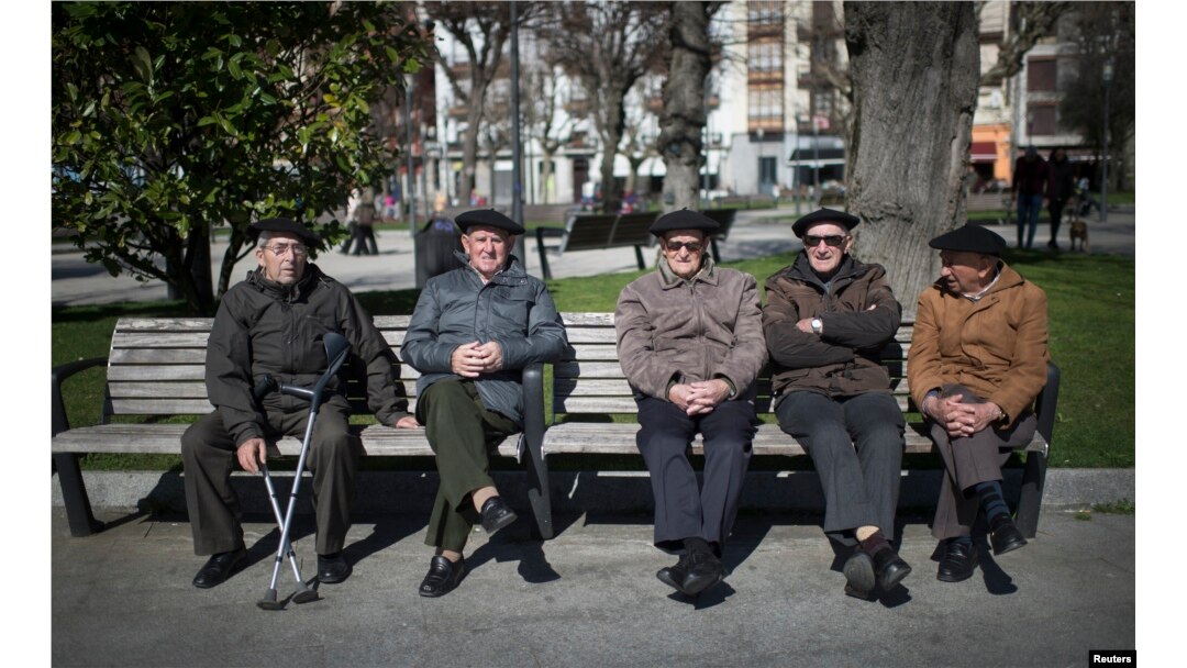 FILE - Retired men sit in the sunshine in the Spanish Basque fishing town of Bermeo, March 6, 2015. Spain's aging population and falling birth rate pose a threat to its future.
