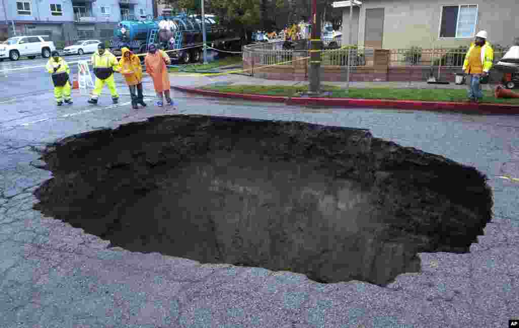 Inspectors examine a sinkhole in Studio City, north of Los Angeles, Feb. 18, 2017. Two vehicles fell into the 20-foot sinkhole on Friday night and firefighters rescued one woman who escaped her car but was found standing on her overturned vehicle. 