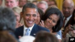 FILE - President Barack Obama and first lady Michelle Obama applaud during the portrait unveiling ceremony for former President George W. Bush and former first lady Laura Bush portraits, May 31, 2012, at the White House in Washington. 