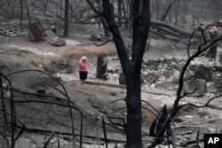 Loretta Root wipes her eyes while visiting the remains of her home in the Keswick area burned in the Carr Fire, Aug. 9, 2018, in Redding, Calif. "It's hard to see this," Root says of her family home. Several of Root's family members living nearby also lost their homes as well.
