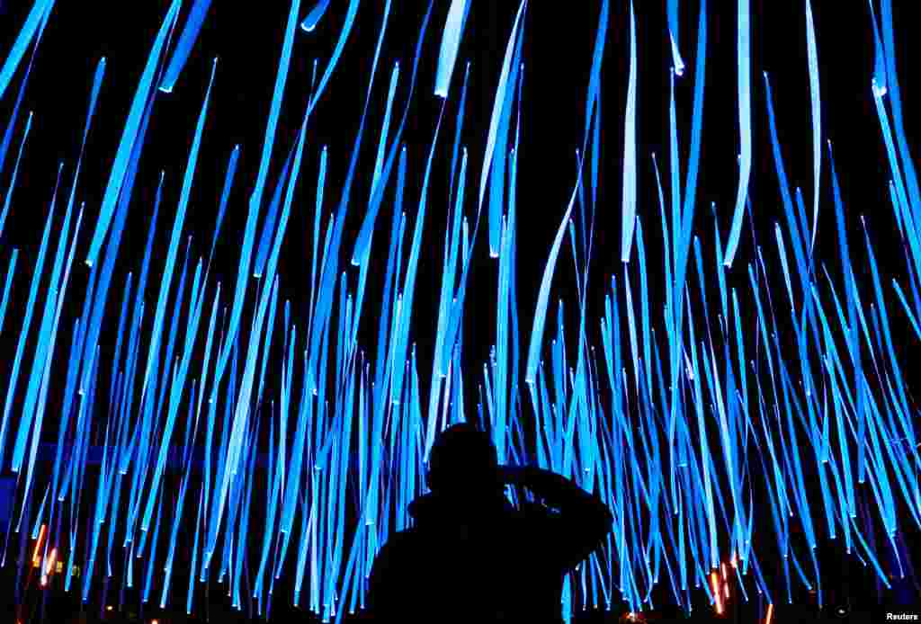 A man takes pictures of an artistic light installation in the Brussels' canal district during the Bright Brussels Festival, Belgium, Feb. 4, 2017.