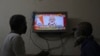 Two people watch a televised address to the nation by Prime Minister Narendra Modi on economic stimulus measures, in Hyderabad, India, May 12, 2020.