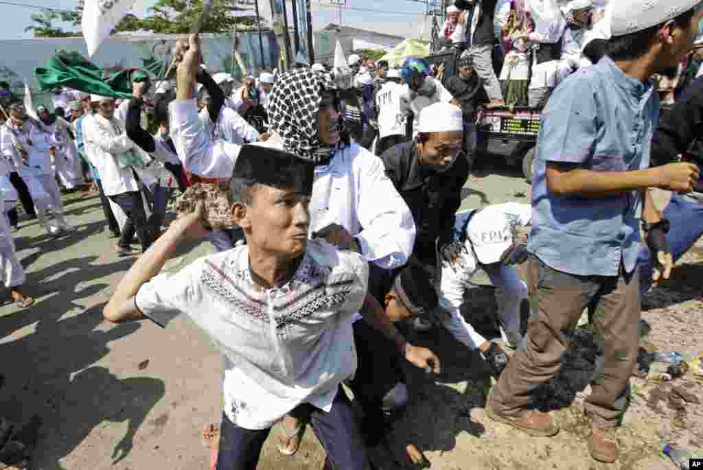 A man throws a rock at police officers during a Muslim hardliner protest against the construction of a Catholic church in Bekasi, Indonesia.
