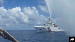 FILE - In this Sept. 23, 2015, photo, a Chinese Coast Guard vessel approaches a Filipino fishing boat as they confront each other off Scarborough Shoal in the South China Sea, also called the West Philippine Sea. 