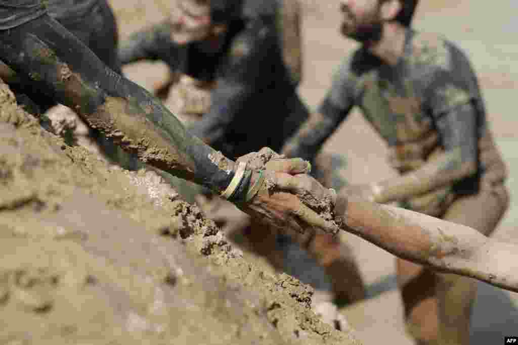 A participant assists another up a hill during the Mud Day Paris 2017 obstacle course in Beynes, France, April 29, 2017.