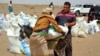 FILE - Yemeni families receive flour rations and other basic food supplies from charities in the province of Lahj, in southern Yemen, March 29, 2022. 
