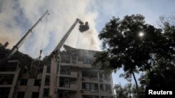 A rescue worker sprays water on an apartment building destroyed in a missile strike, amid Russia's invasion of Ukraine, in Kyiv, June 26, 2022. 