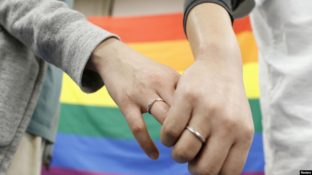 FILE - Plaintiffs hold each others' hands after a district court ruled on the legality of same-sex marriages, outside Sapporo district court, in Sapporo, Hokkaido, northern Japan, March 17, 2021. (Kyodo/via Reuters)