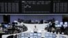 Traders are pictured at their desks in front of the DAX board at the Frankfurt stock exchange, August 14, 2012. 