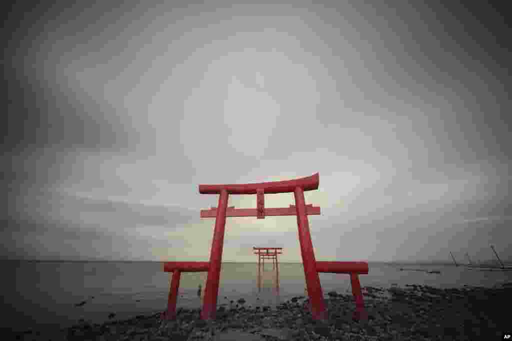 Small shrine arches or "Torii" gates stand on the shore and out into the Ariake Sea in Tara, Saga Prefecture, southwestern Japan.