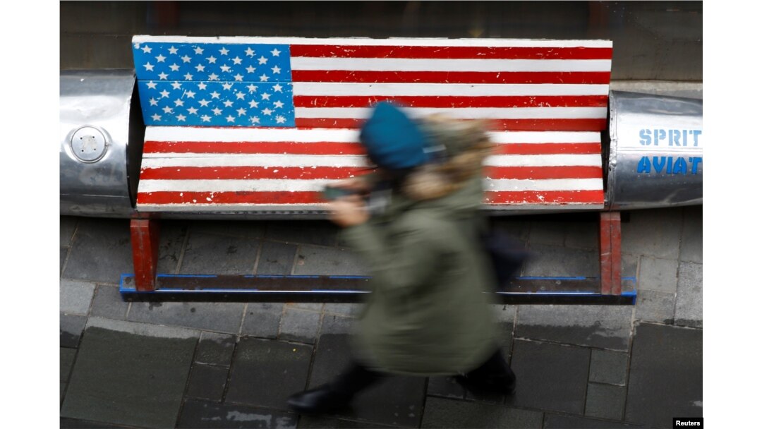 A woman walks past a bench painted in the colors of the U.S. flag, outside a clothing store in Beijing, China, Jan. 7, 2019.