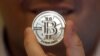 FILE - Mike Caldwell, a 35-year-old software engineer, holds a 25 Bitcoin token at his shop in Sandy, Utah. 