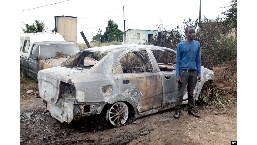 A foreign national from Zimbabwe stands by one of his two cars set alight after he survived a petrol bomb attack at his home in Illovo, some 55 kilometers south of Durban, South Africa, April 19, 2015