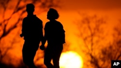  In this Wednesday, March 10, 2021 file photo, a couple walks through a park at sunset in Kansas City, Missouri, USA. According to a new report, U.S. life expectancy fell by a year and a half in 2020, the largest one-year decline since World War II. (AP Photo/Charlie Riedel)