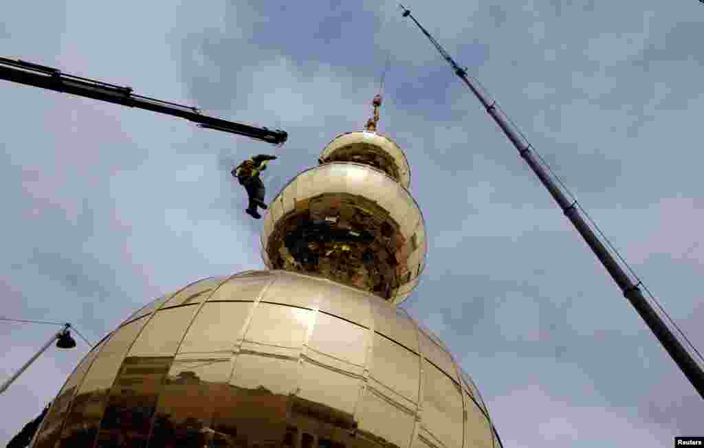 Palestinian workers prepare a golden crescent to set it on top of the minaret of a new mosque in the East Jerusalem neighborhood of Issawiya.