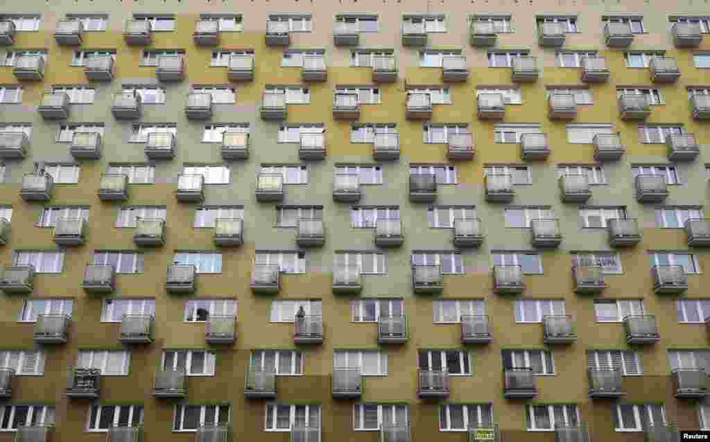 A woman smokes a cigarette as she looks out from her apartment balcony in Gdynia, Poland.
